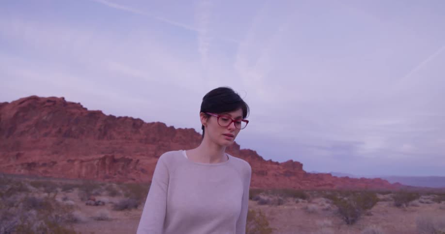 A woman walks in the desert on a cloudy day