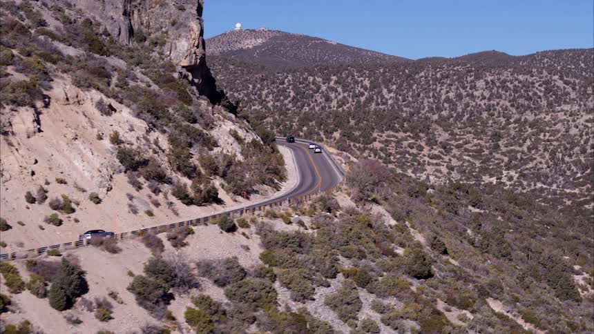 A silver car drives past the hills