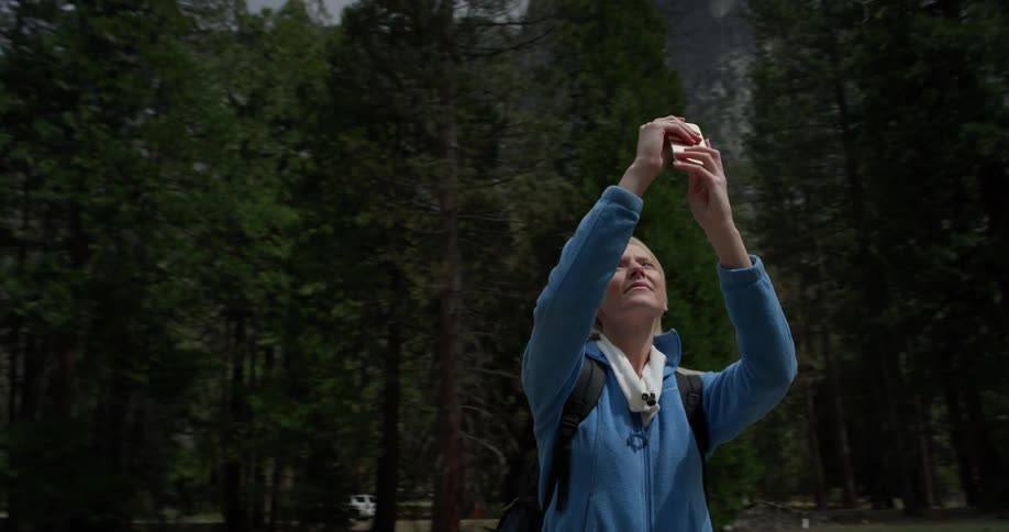Woman is photographing mountain scenery in yosemite on cloudy day