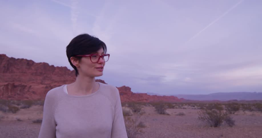A woman wearing glasses walks in the desert