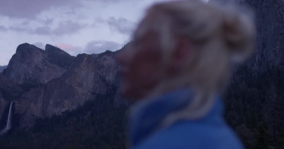 A woman looks around at the mountainous landscape