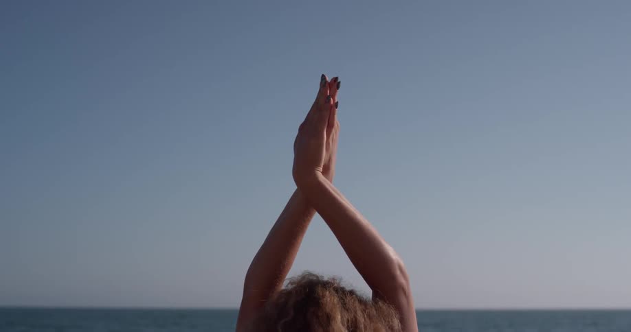 Woman is stretching and doing yoga next to the ocean