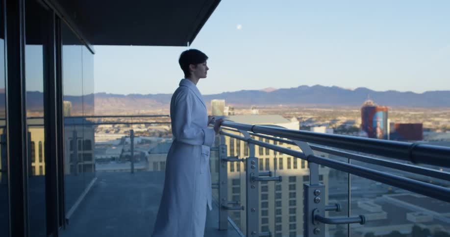 A woman exits her home to go on the balcony