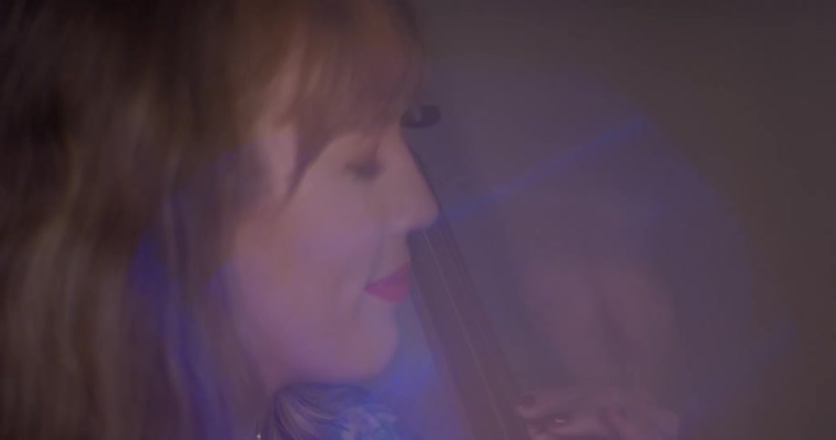 A woman is playing a cello inside in daylight