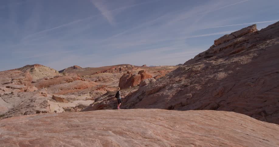 Woman walks over rocky hills on a clear day