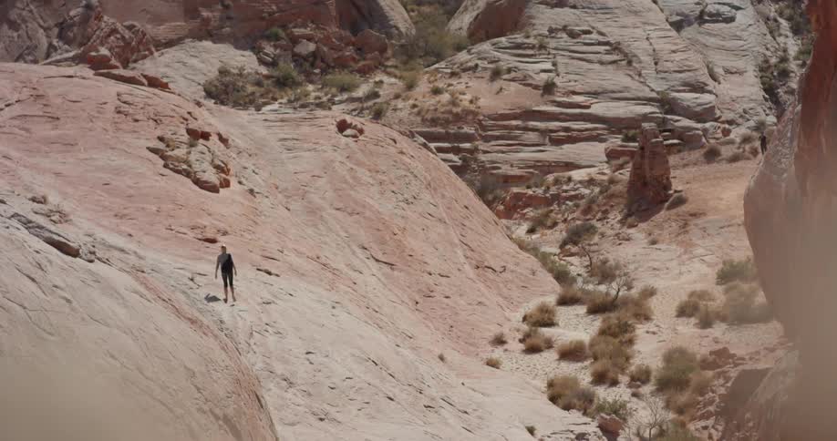 Person walks on rocky hilly land on a sunny day