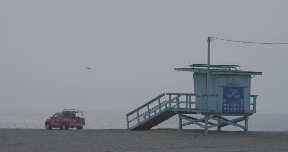 A truck is parked next to a lifeguard tower on a beach