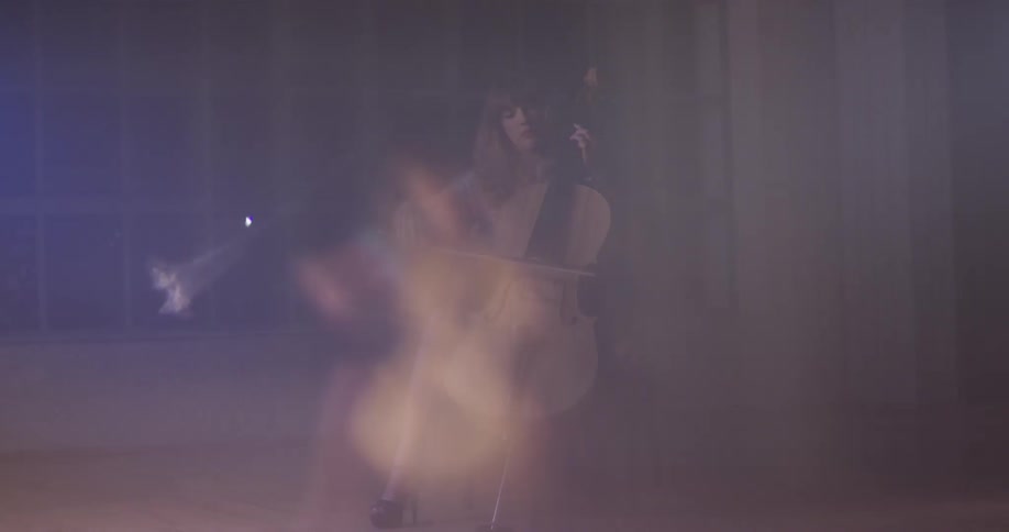 Woman plays a cello in blurry light in a room at night