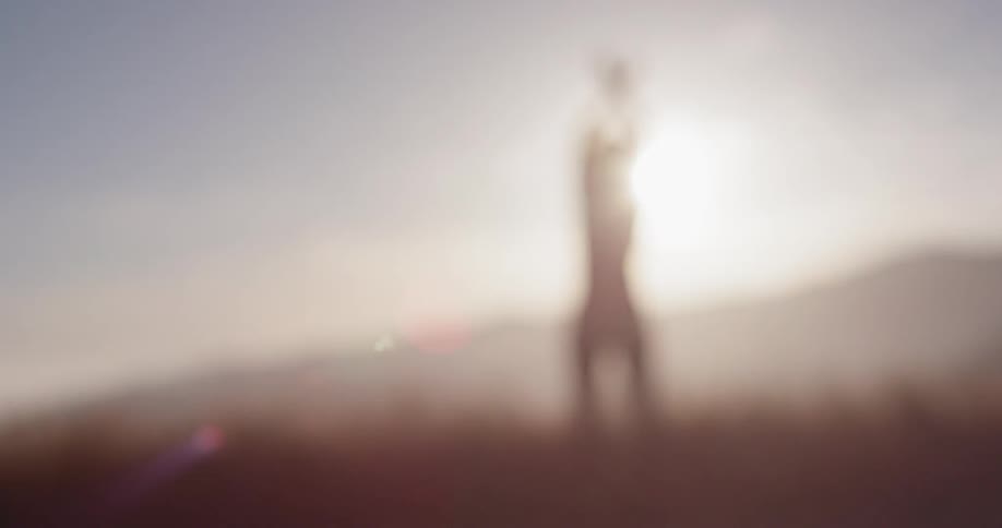 A woman stretches her arms up as the sun shines