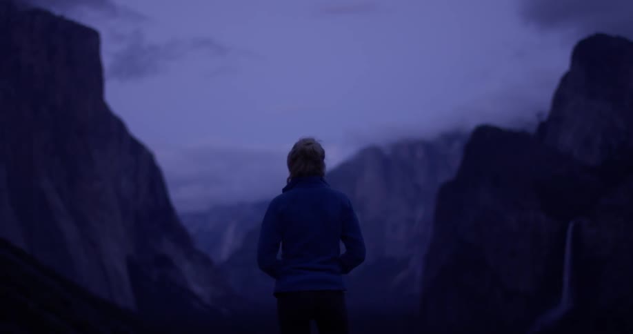 The woman is looking around the mountain range at dawn