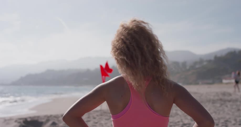 A woman stands on the beach as the tide rolls in