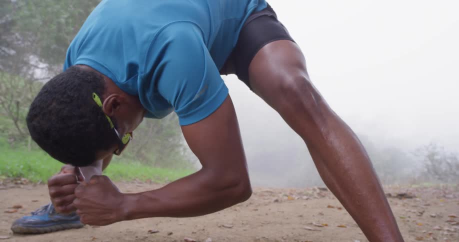 A woman leans over to stretch on a dirt trail