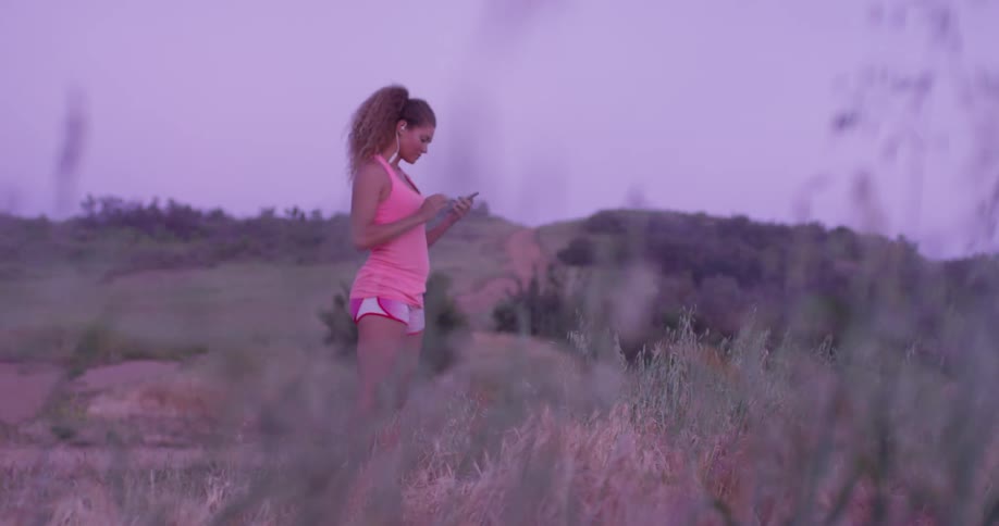 Woman walks outside and looks down at her phone