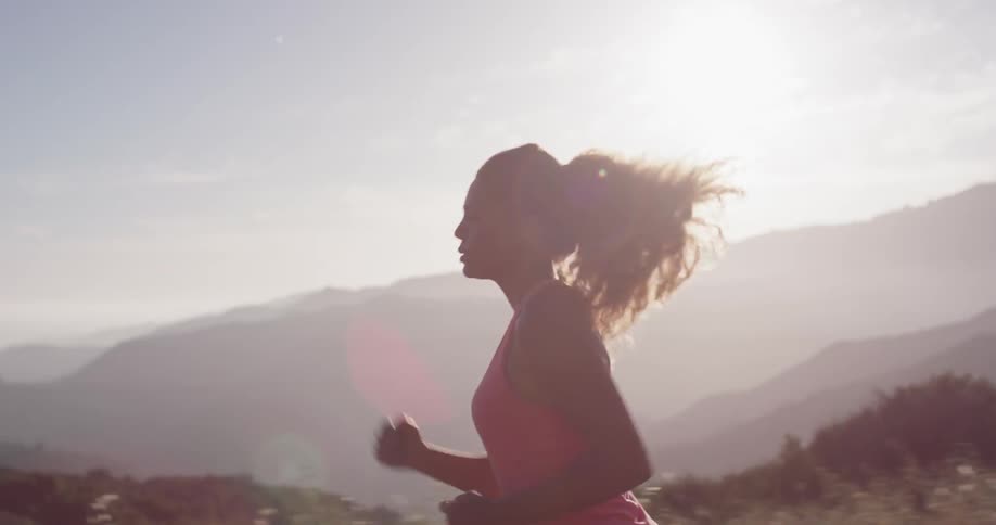 Woman is jogging near mountains as sun sets