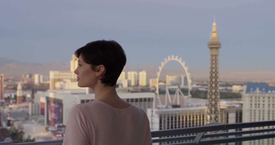 A woman looks at the large buildings of the city from the balcony
