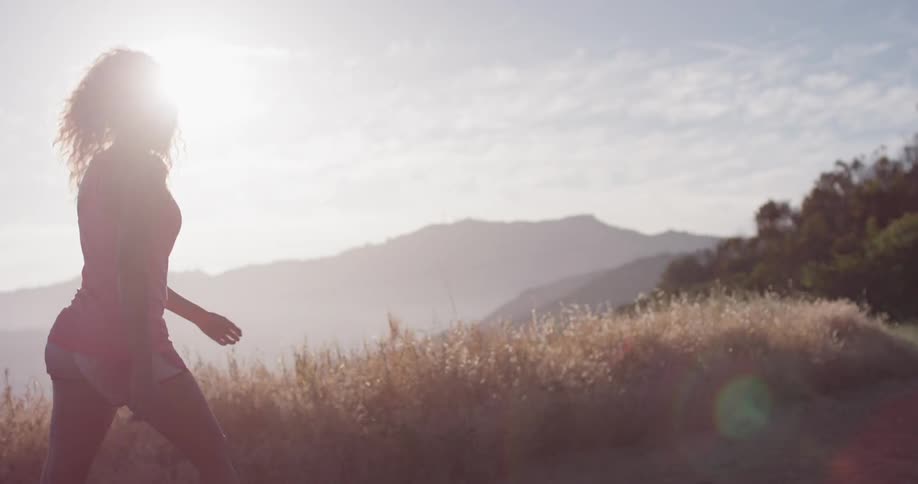 A woman walks along a grass ridge and then starts to jog