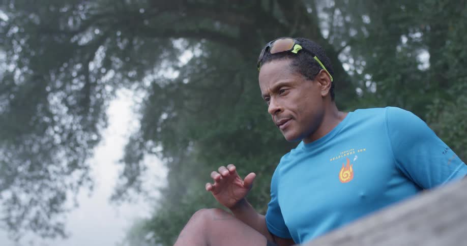 Man stretches outside near trees on a cloudy day