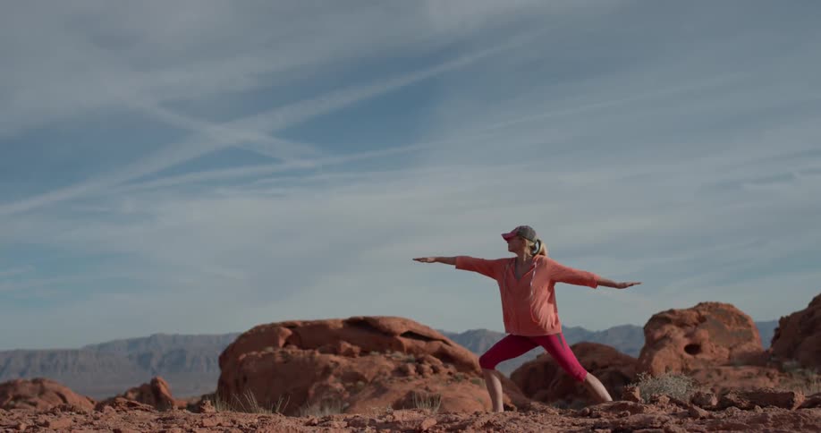 A woman does yoga on top of the mountain