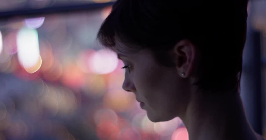 Woman wearing stud earrings blinks her eyes as she looks downwards