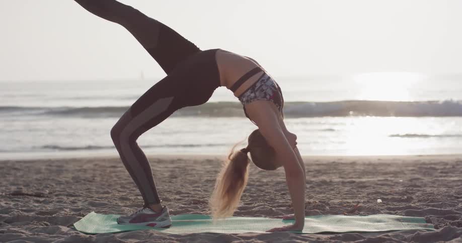 A woman does yoga on a beach