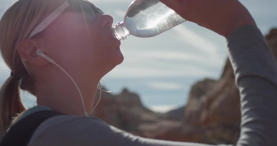 A woman is gulping a bottle of water
