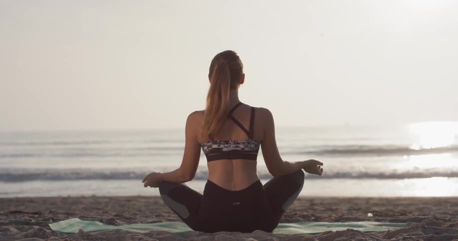 Woman Doing Yoga On The Beach