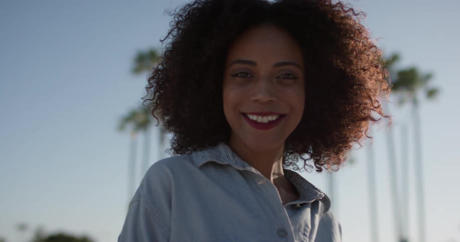 A woman smiles outside under the sun