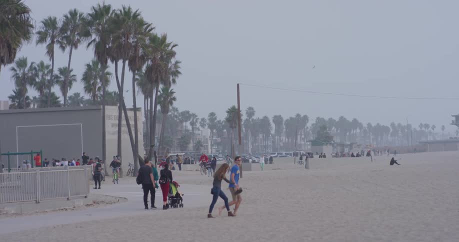 Crowd of people walk on a sandy beach