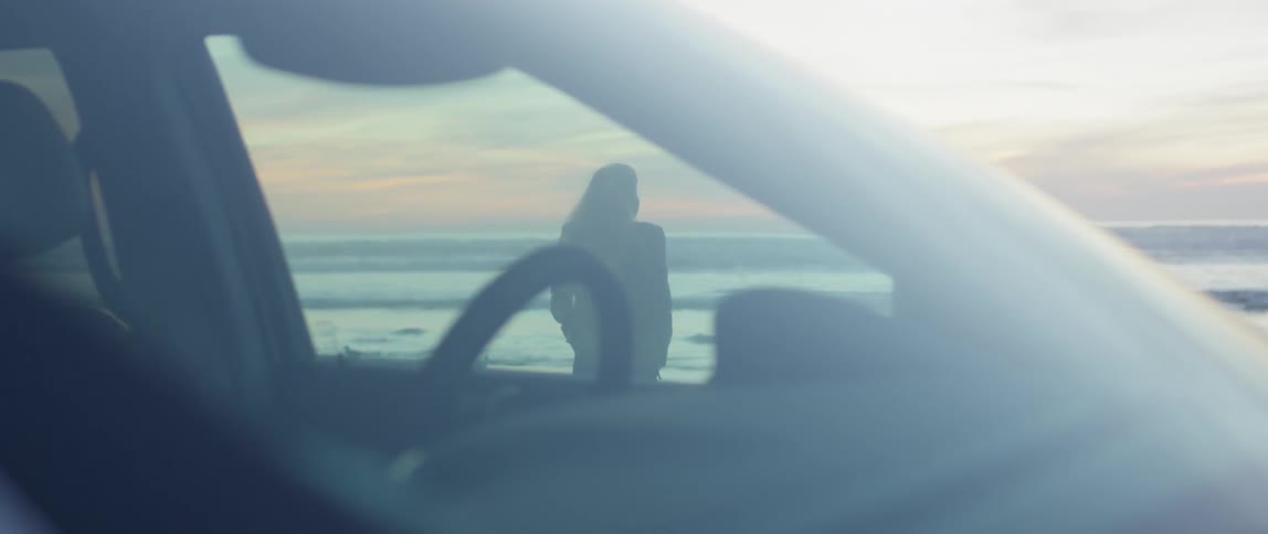 A woman stands on a beach at sunset