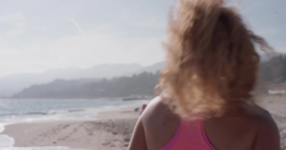 Woman jogs on a beach on a sunny day