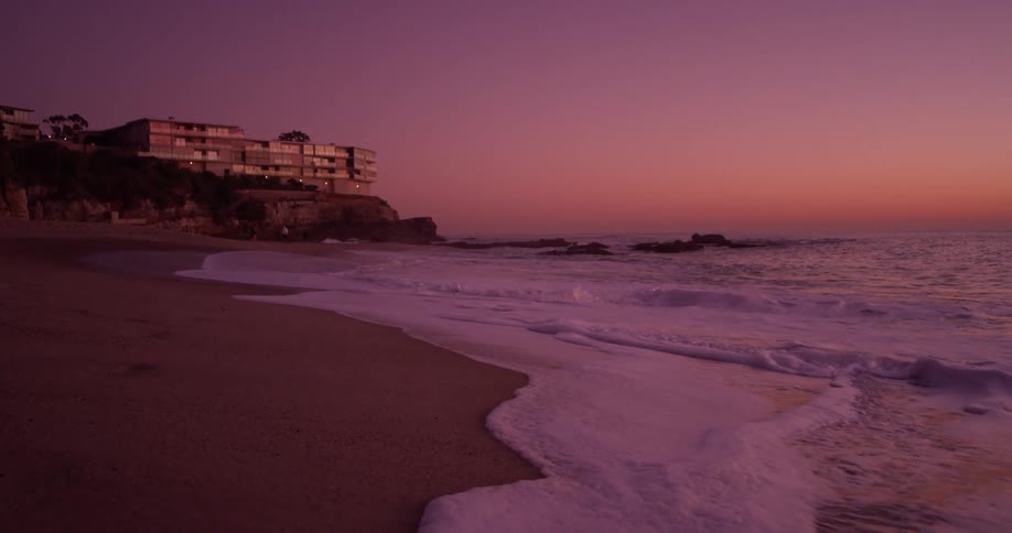 The waves crash against the coastal town at dawn