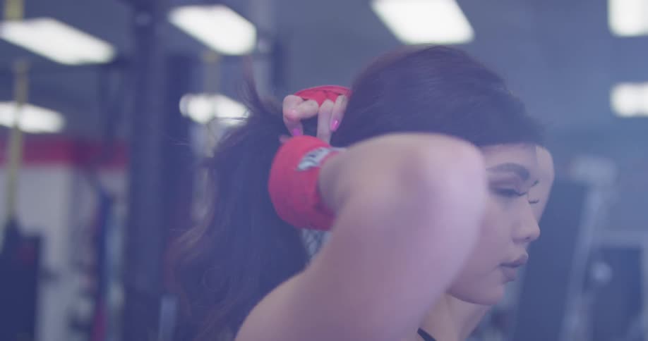 Woman standing in a gym puts her hair up