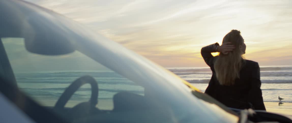 A woman gets out of the car by the water