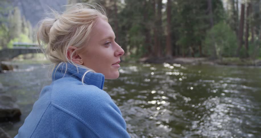 The woman smiles looking out over the stream