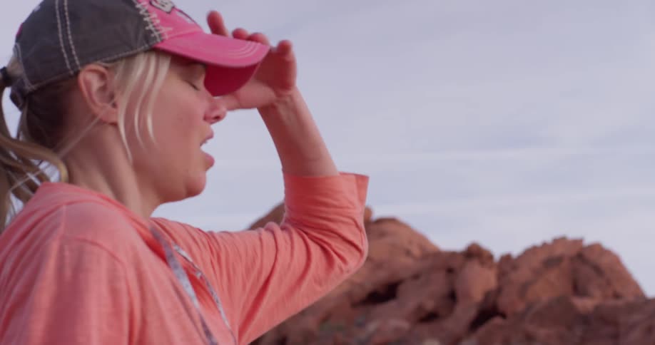 A blond haired woman catches her breath and removes her hat