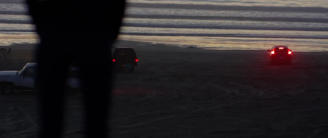 A woman stands on a beach at sunset
