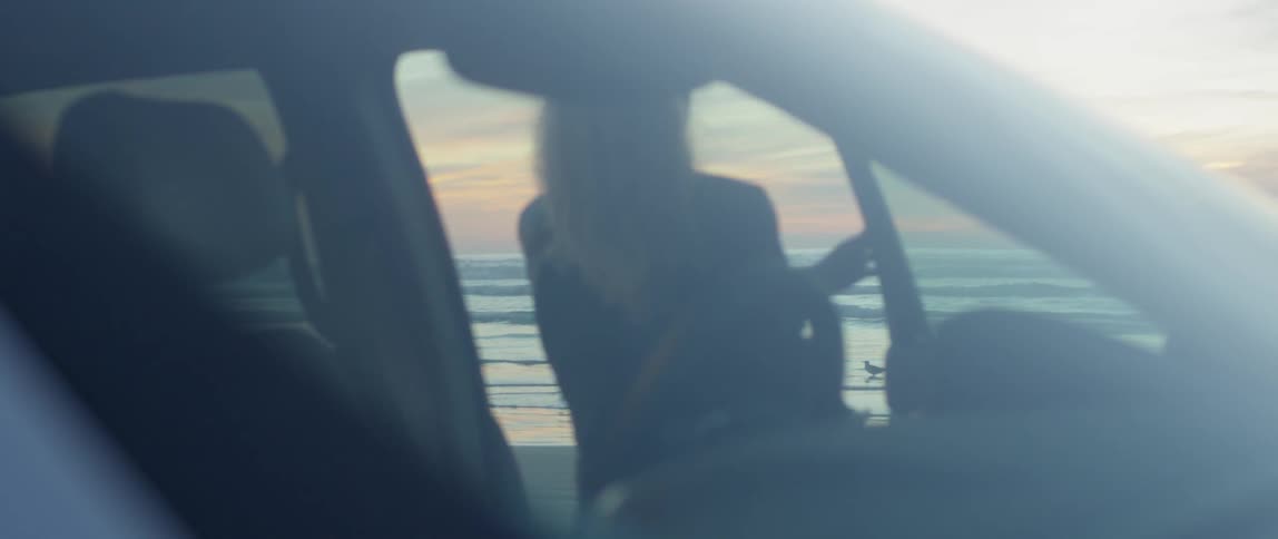 A woman parks on a beach at sunset
