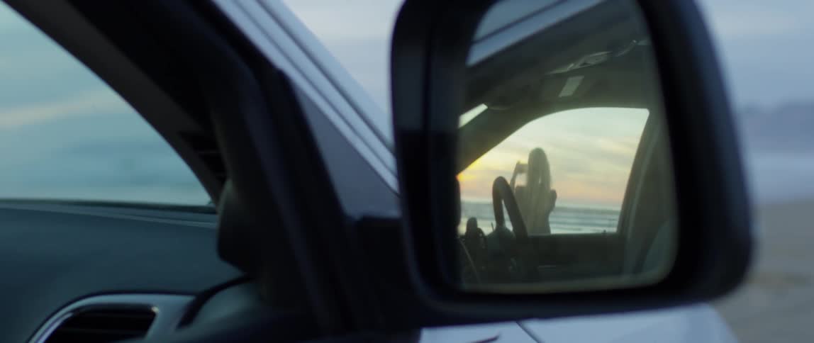 The rear view mirror shows a woman taking a photo