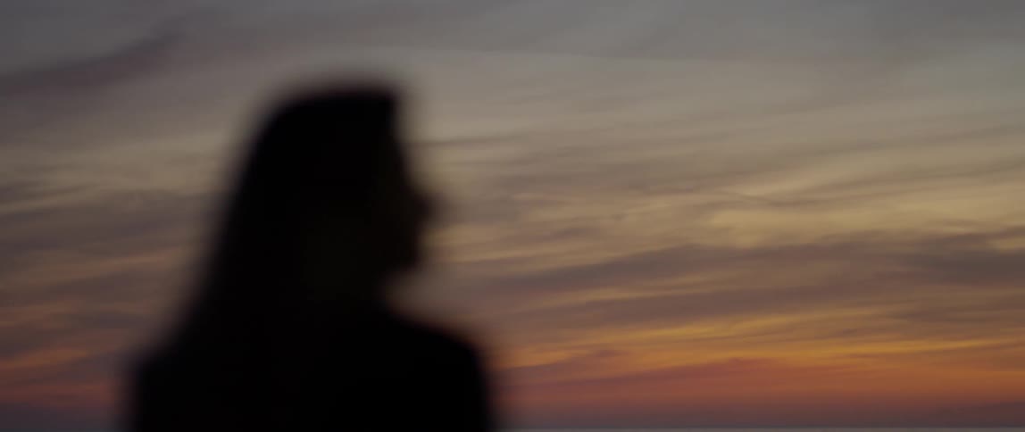 Woman stands on the beach at sunset