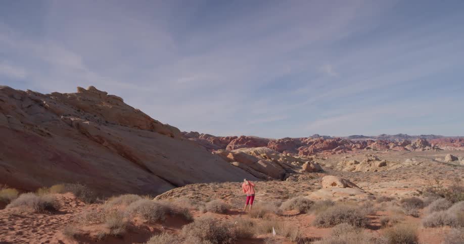 A person stands in the desert near the hill