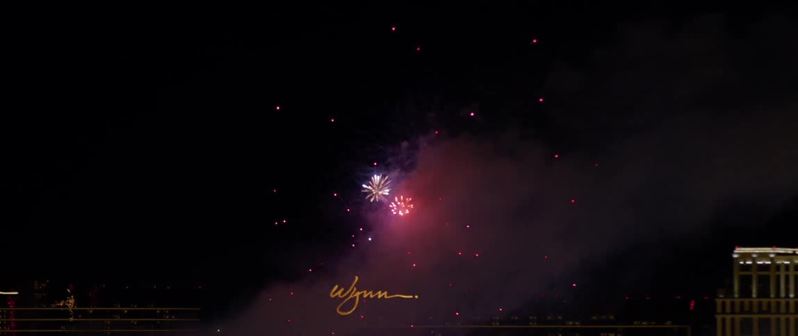 Fireworks explode in the night sky above a hotel