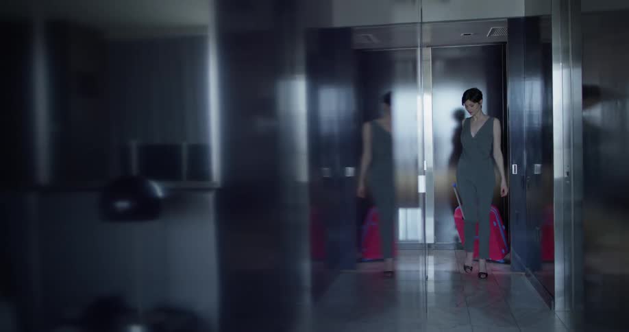 A woman rolls a suitcase in a hallway