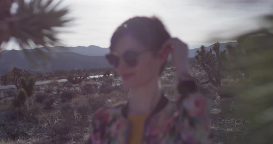 A woman brushes her hair in the desert