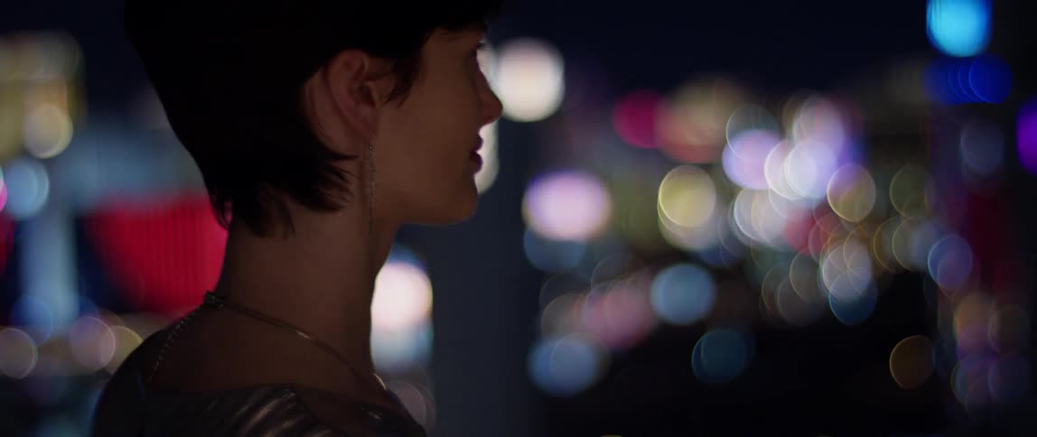 Woman looks out at the lit up city at night