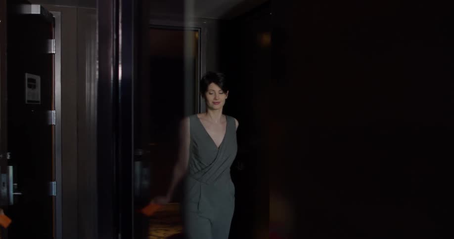 A woman enters a hotel room with luggage