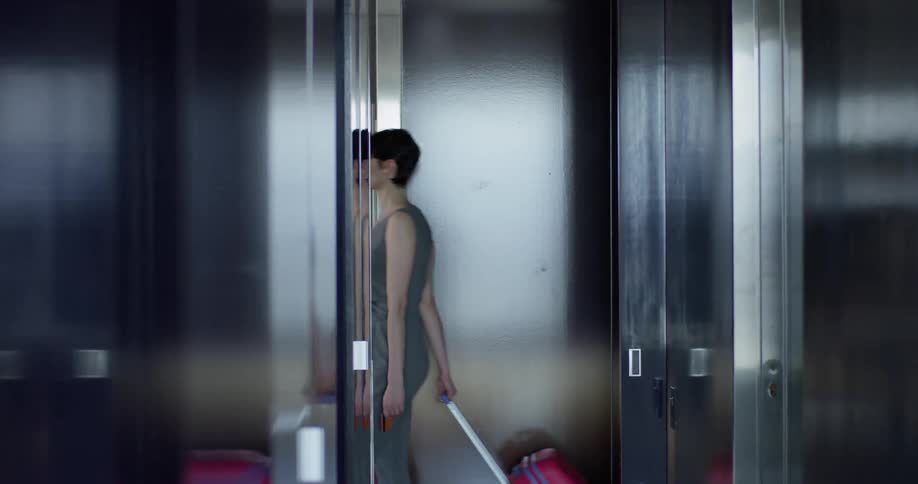 Woman walks down the hallway of an office building pulling a suitcase