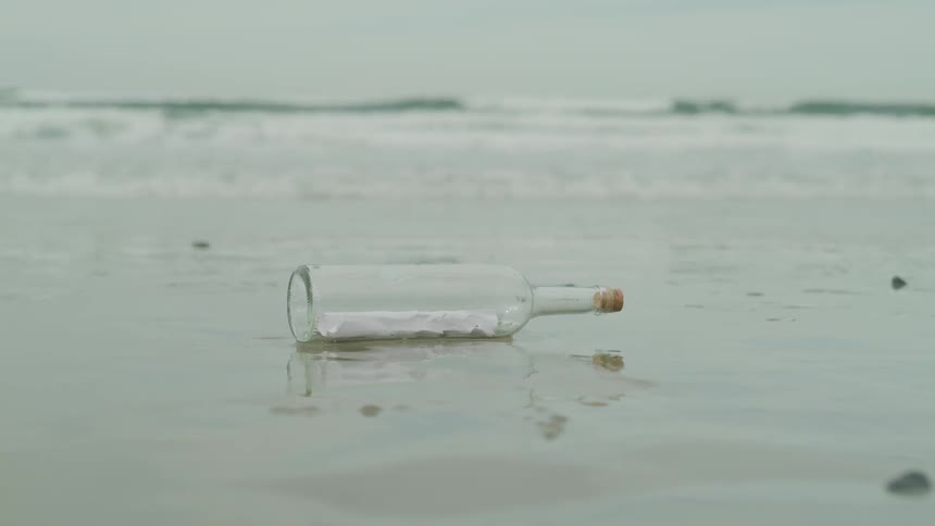 A note in a bottle lays on the beach