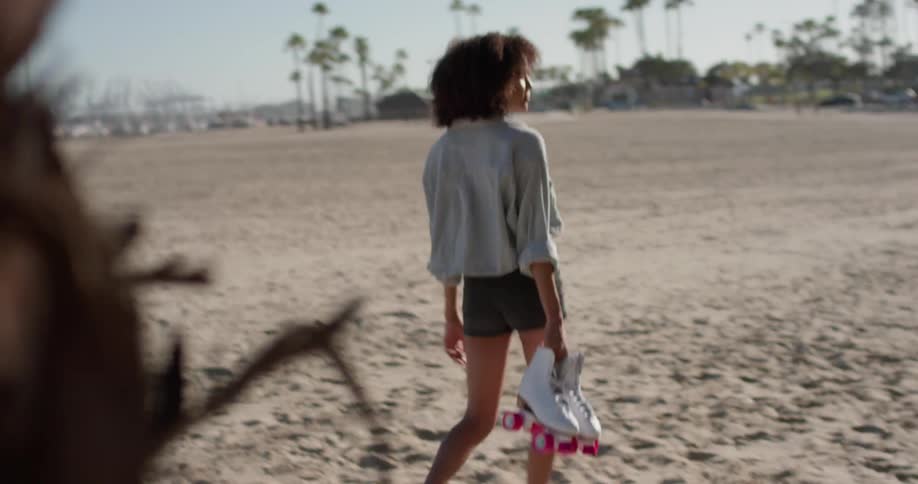 A woman carries roller skates on the beach