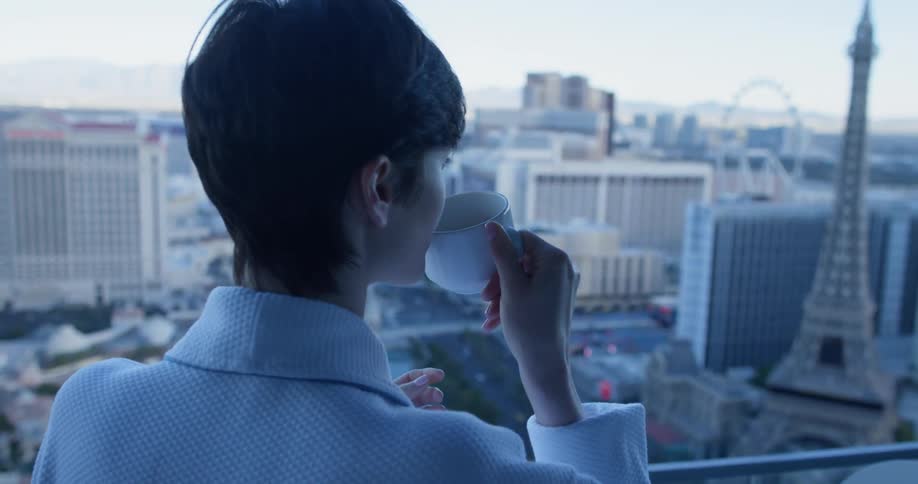 Woman drinks a cup of coffee as she looks out at the city
