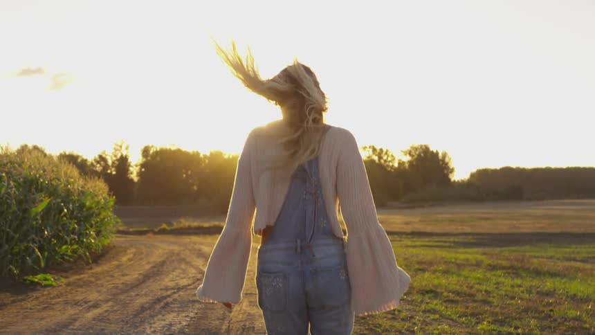 A woman walks on a farm at sunset
